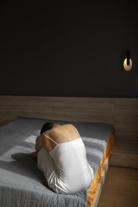 Mlada žena sedi na krevetu – prevazilaženje usamljenosti i osećaj izolacij